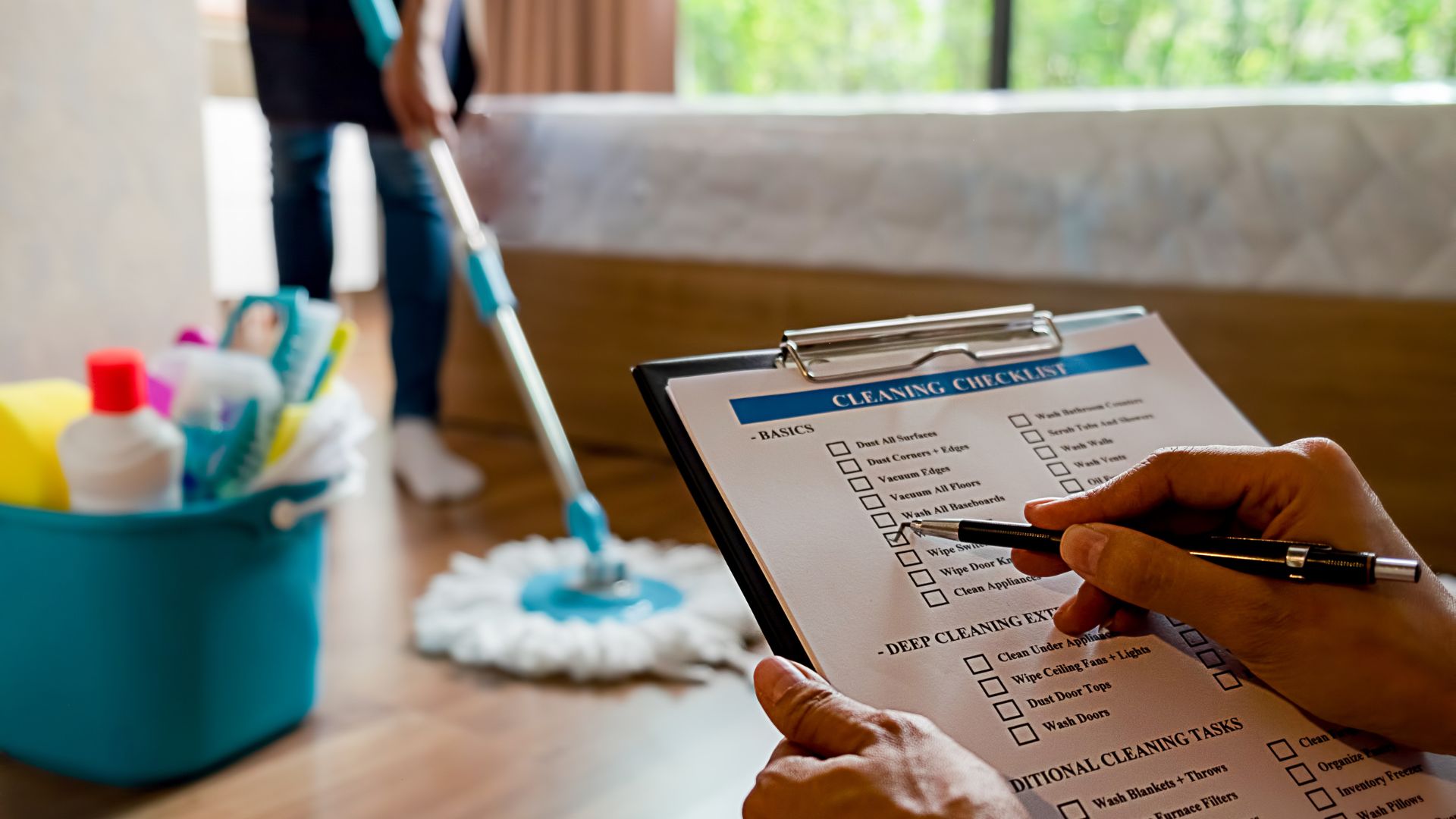 Person filling out cleaning checklist with supplies and mop in background