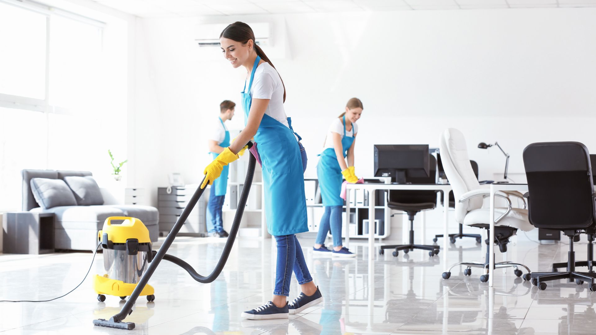 Cleaning staff using vacuum in modern office with professional equipment