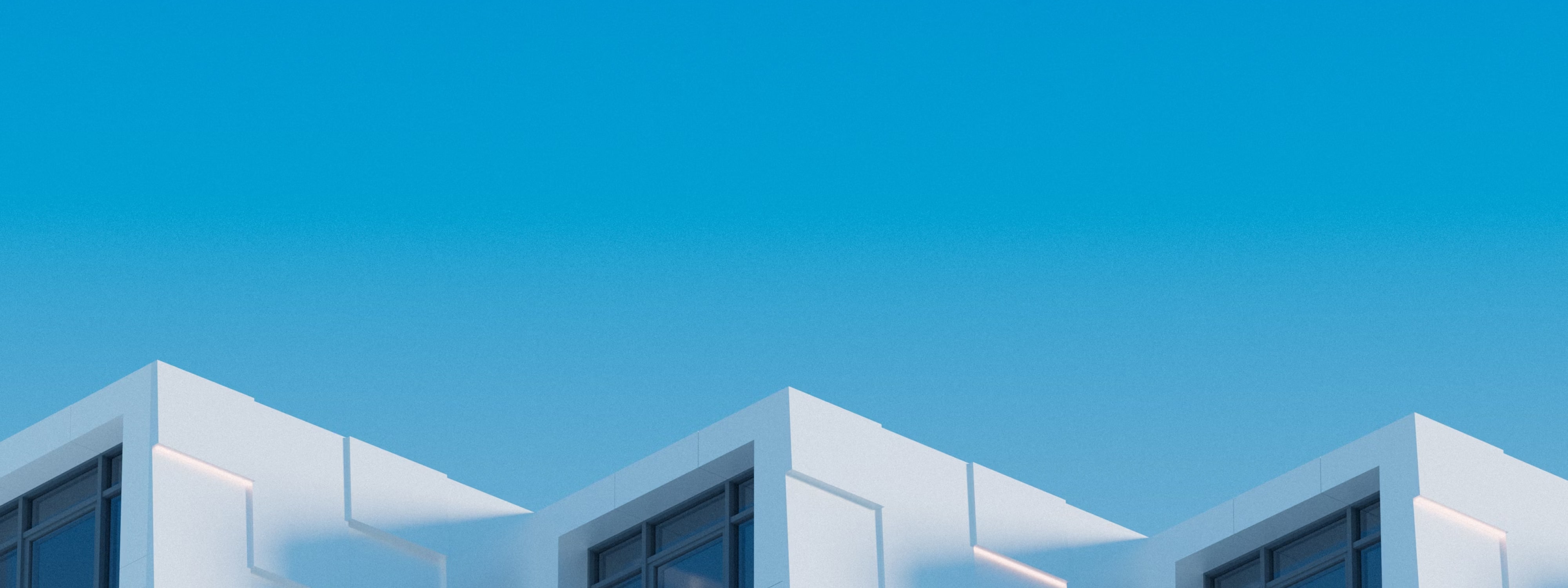 Minimalist white buildings against a clear blue sky